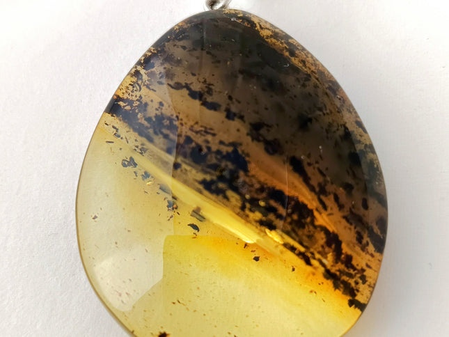 großer gelb-schwarzer Tropfen aus Bernstein mit einer schräg verlaufenden Banderole aus Einschlüssen, fast wie die Ringe des Saturn Tikiwe Bernsteinschmuck