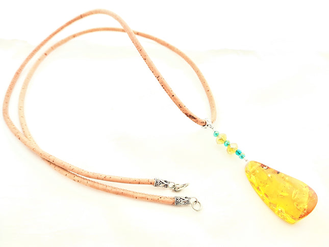 tropfenförmiger, honigfarbener Bernstein an einer ca. 80 cm langen Kordel aus Kork. Im Bernstein sind wunderschöne Einschlüsse, die ihm eine interessante Optik verleihen. Handmade by Tikiwe-Taschen aus Kork