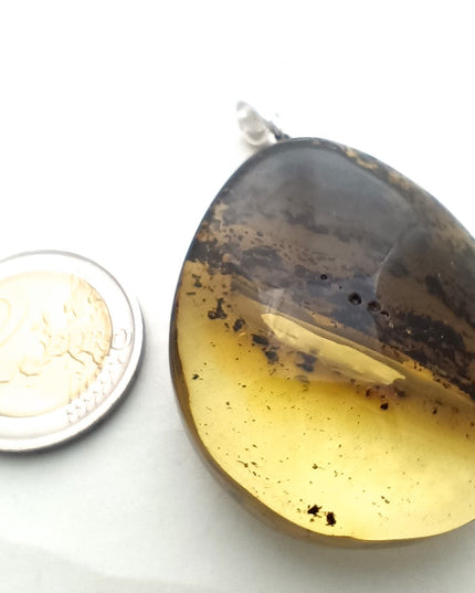 Tikiwe Bernsteinschmuck Größenverhältnis
großer gelb-schwarzer Tropfen aus Bernstein mit einer schräg verlaufenden Banderole aus Einschlüssen, fast wie die Ringe des Saturn Tikiwe Bernsteinschmuck