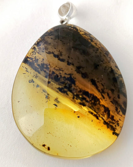 großer gelb-schwarzer Tropfen aus Bernstein mit einer schräg verlaufenden Banderole aus Einschlüssen, fast wie die Ringe des Saturn Tikiwe Bernsteinschmuck