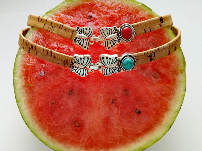 2 Choker / Armbänder aus Kork mit einer Schmetterlingschließe und rotem, türkisem Stein auf eine Melone