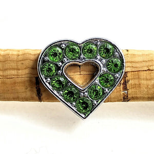 Herz aus Edelstahl mit grünen Glitzersteinchen auf einem Band aus Kork