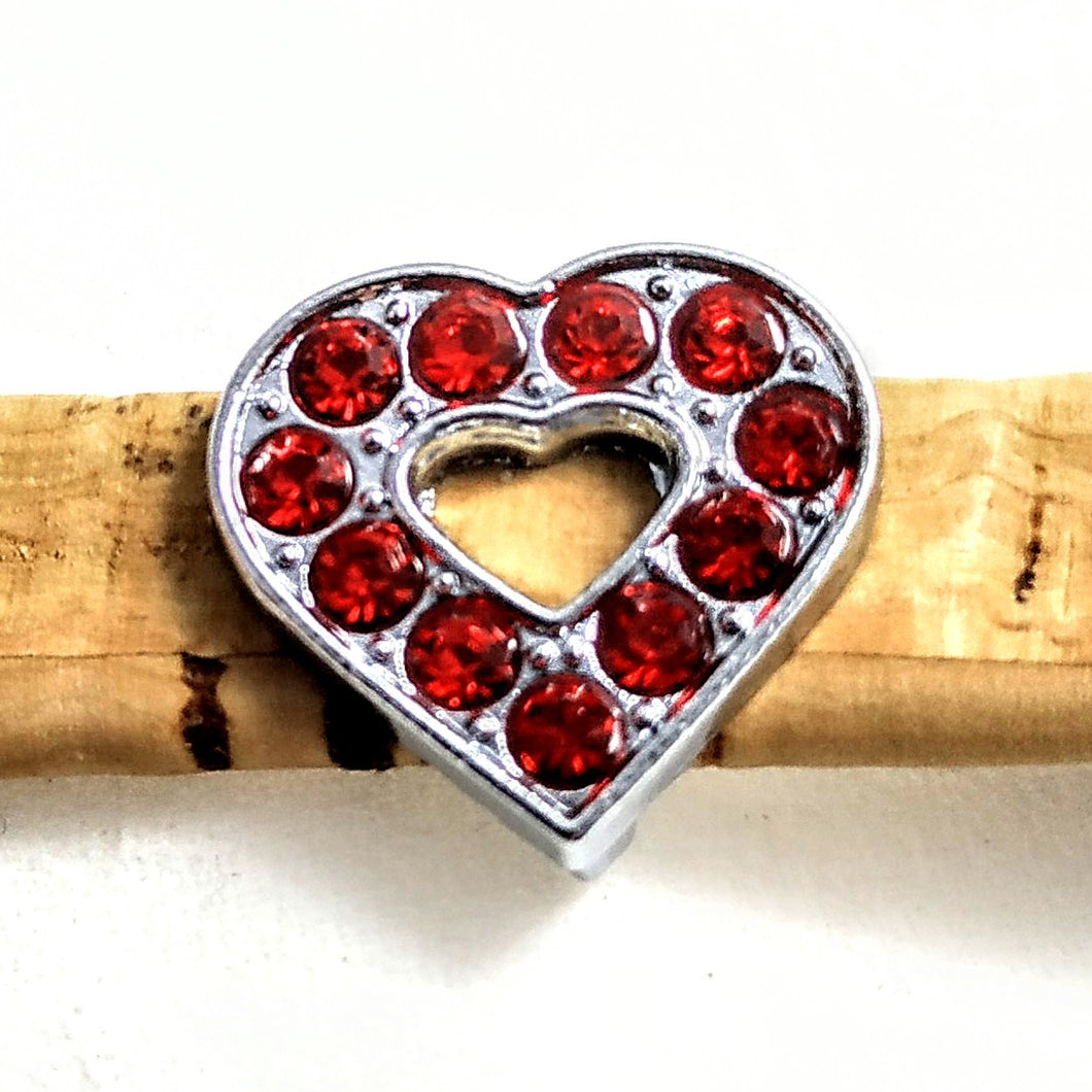 Herz aus Edelstahl mit roten Glitzersteinchen auf einem Band aus Kork
